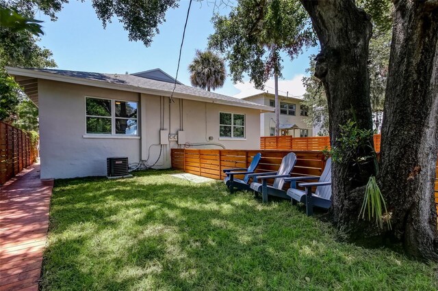 rear view of house with central AC, a wooden deck, and a yard