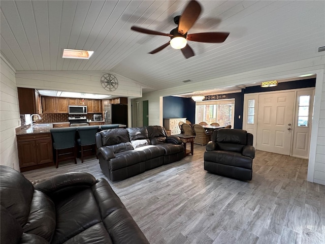 living room with ceiling fan, sink, vaulted ceiling, wood ceiling, and light wood-type flooring