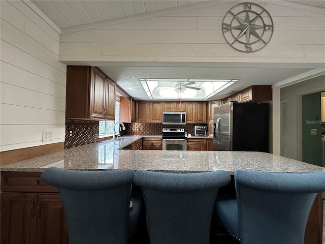 kitchen featuring ceiling fan, sink, kitchen peninsula, lofted ceiling, and appliances with stainless steel finishes