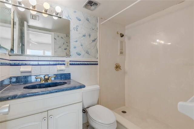 bathroom featuring tile walls, vanity, ceiling fan, walk in shower, and toilet