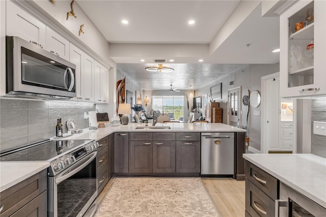 kitchen with sink, white cabinets, stainless steel appliances, and light hardwood / wood-style floors