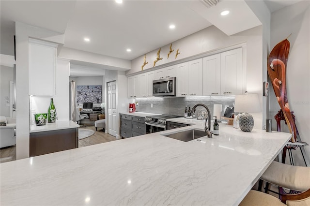 kitchen featuring backsplash, a kitchen breakfast bar, sink, kitchen peninsula, and stainless steel appliances