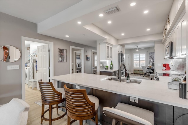 kitchen featuring a breakfast bar area, kitchen peninsula, white cabinetry, and sink