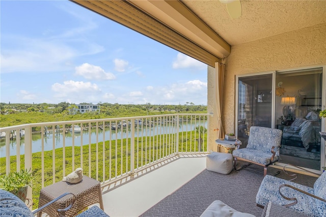 balcony with ceiling fan and a water view