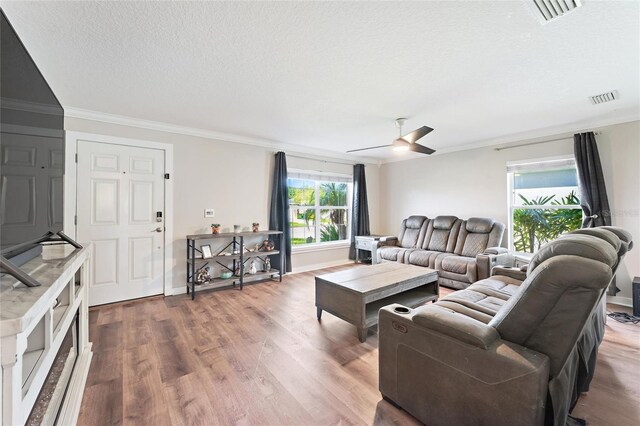 living room featuring a textured ceiling, ceiling fan, crown molding, and wood-type flooring