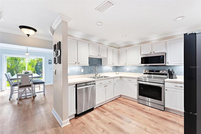 kitchen with appliances with stainless steel finishes, light hardwood / wood-style floors, white cabinets, and sink