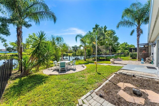 view of yard with a water view, a trampoline, and a patio area