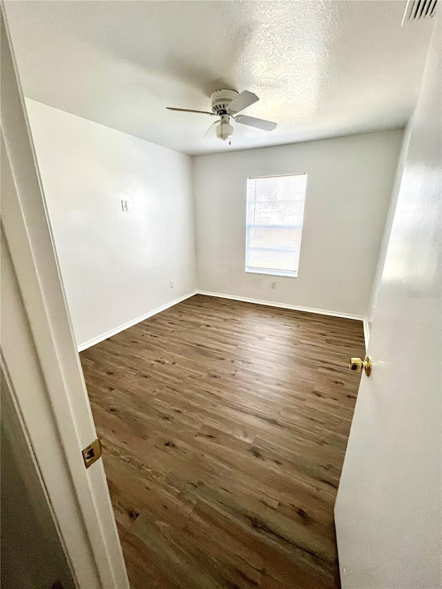 spare room with a textured ceiling, ceiling fan, and dark wood-type flooring