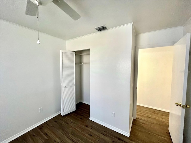 unfurnished bedroom with ceiling fan, a closet, dark wood-type flooring, and ornamental molding