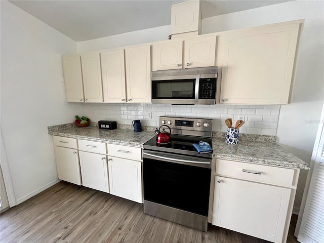 kitchen featuring white cabinets, light hardwood / wood-style flooring, decorative backsplash, light stone counters, and stainless steel appliances