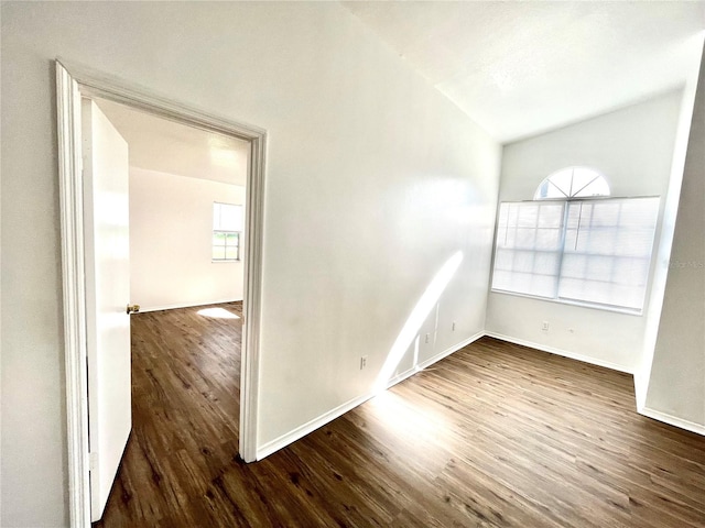 empty room with dark hardwood / wood-style flooring and vaulted ceiling