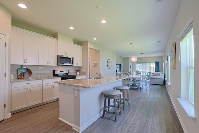 kitchen featuring a center island with sink, white cabinets, hardwood / wood-style flooring, and appliances with stainless steel finishes