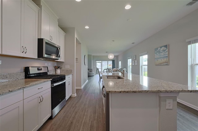 kitchen with sink, stainless steel appliances, white cabinetry, and a center island with sink