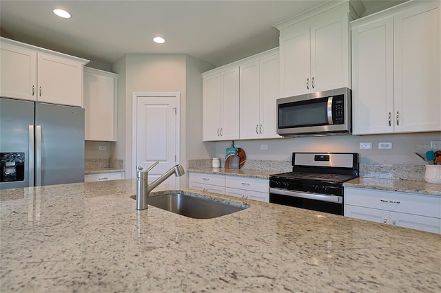 kitchen with sink, white cabinets, light stone countertops, and stainless steel appliances