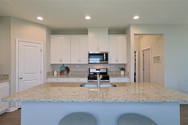 kitchen with white cabinets, stainless steel appliances, and an island with sink