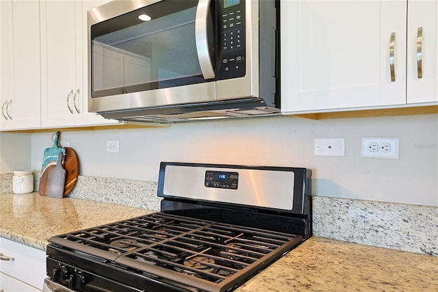 kitchen with white cabinetry, light stone countertops, and gas stove