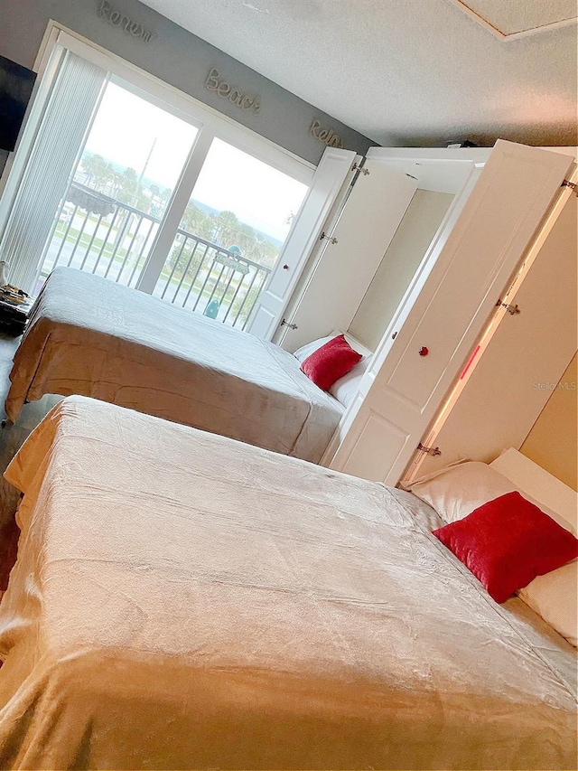 bedroom featuring access to exterior, carpet, and a textured ceiling