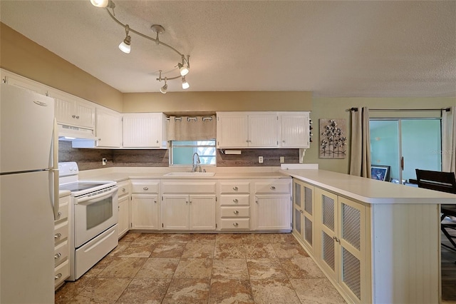 kitchen featuring under cabinet range hood, a peninsula, white appliances, a sink, and light countertops