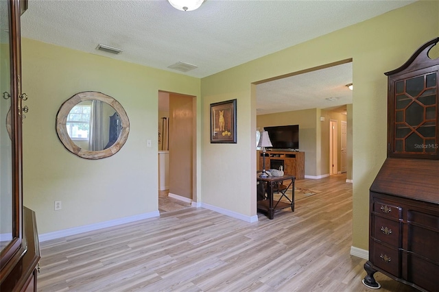 interior space featuring light wood-type flooring, visible vents, and a textured ceiling