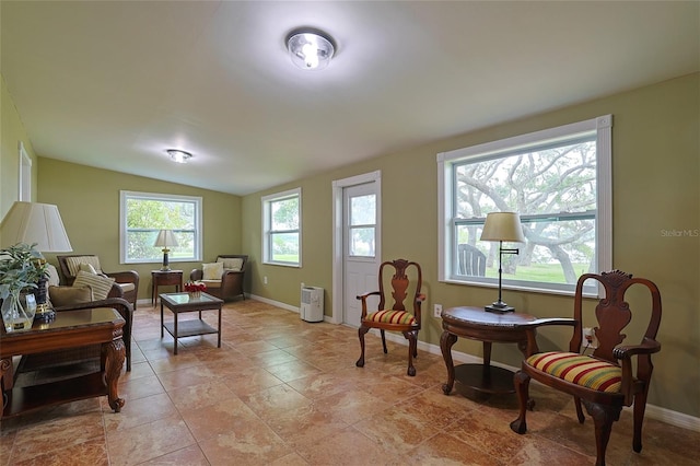 living area featuring lofted ceiling and baseboards