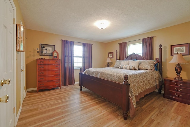 bedroom featuring light wood-type flooring, a textured ceiling, and baseboards