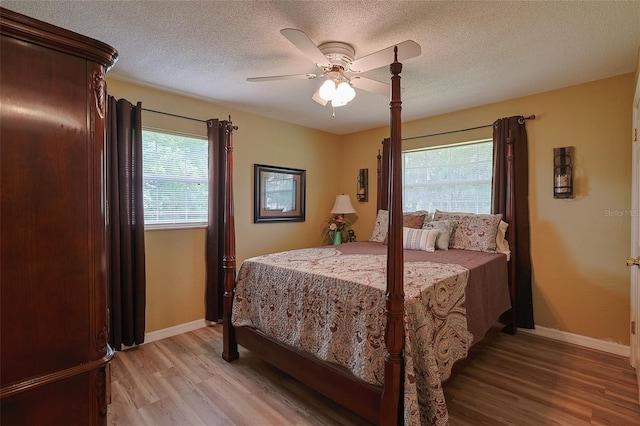 bedroom with light wood finished floors, baseboards, a ceiling fan, and a textured ceiling