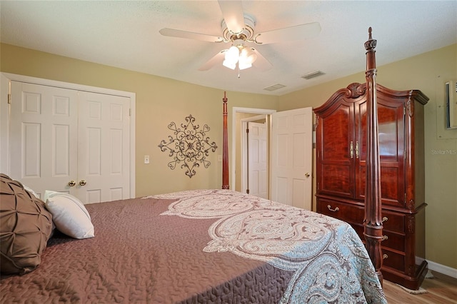 bedroom featuring ceiling fan, wood finished floors, visible vents, baseboards, and a closet