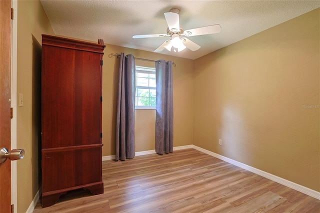 unfurnished bedroom with light wood finished floors, baseboards, and a textured ceiling