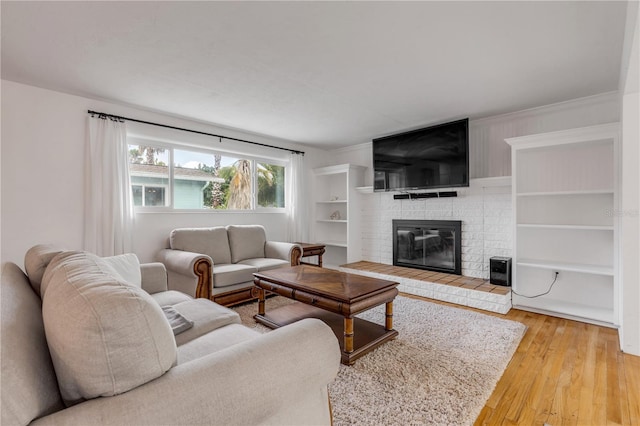 living room with a brick fireplace and light hardwood / wood-style floors