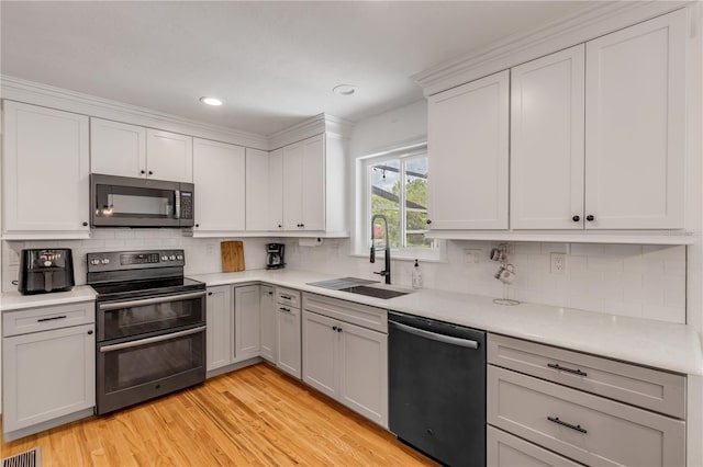 kitchen featuring decorative backsplash, dishwashing machine, range with two ovens, light wood-type flooring, and sink
