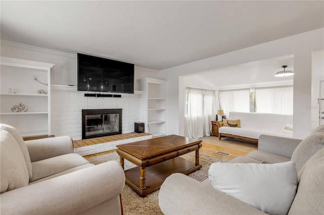 living room with crown molding, light hardwood / wood-style floors, and a fireplace