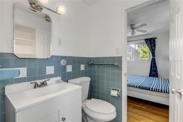 bathroom with ceiling fan, vanity, tile walls, toilet, and hardwood / wood-style flooring