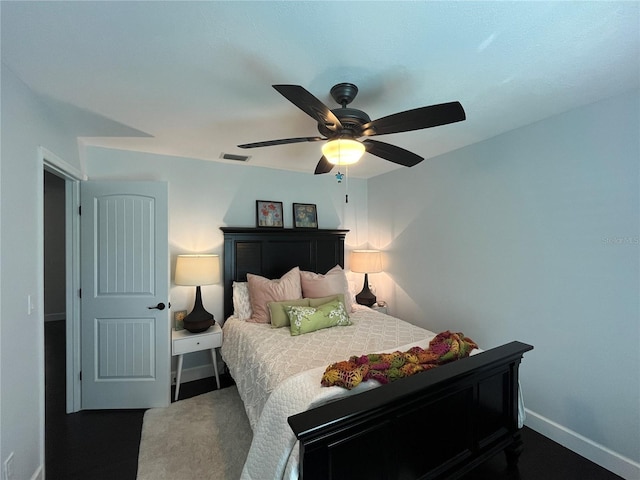 bedroom featuring visible vents, a ceiling fan, baseboards, and dark colored carpet