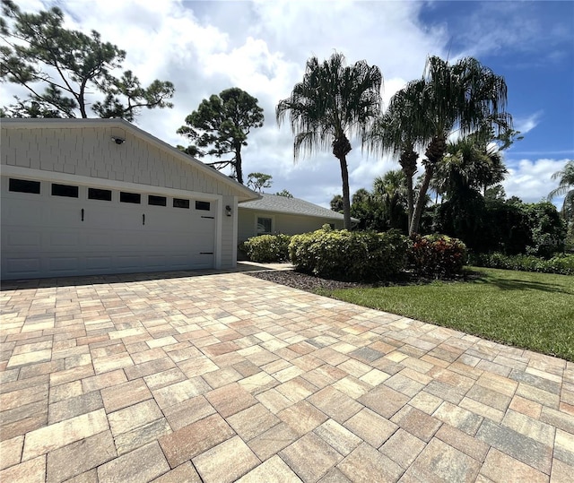 exterior space with a front lawn, decorative driveway, and an attached garage