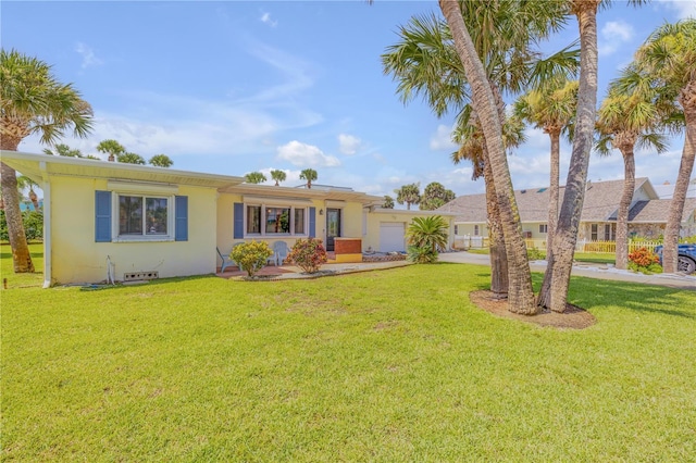 ranch-style home with driveway, a front yard, an attached garage, and stucco siding