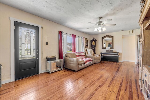 living area featuring ceiling fan, light wood-type flooring, and baseboards