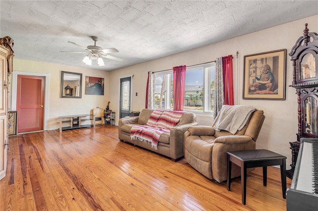 living area with light wood-style flooring, a ceiling fan, and a textured ceiling