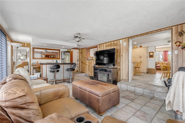 living area featuring recessed lighting, light tile patterned flooring, ceiling fan, wooden walls, and a textured ceiling