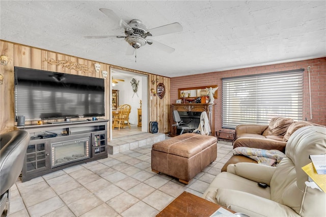 living area featuring light tile patterned floors, a textured ceiling, a fireplace, and a ceiling fan