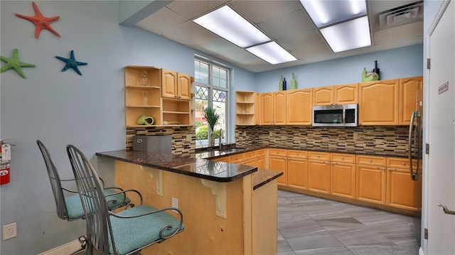 kitchen with appliances with stainless steel finishes, tasteful backsplash, sink, kitchen peninsula, and light tile patterned floors