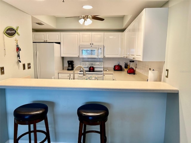 kitchen featuring white cabinetry, white appliances, kitchen peninsula, ceiling fan, and decorative backsplash