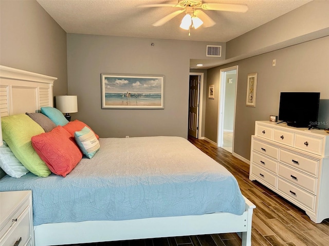 bedroom with a textured ceiling, ceiling fan, and wood-type flooring