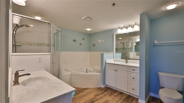 full bathroom featuring a textured ceiling, toilet, vanity, shower with separate bathtub, and hardwood / wood-style flooring