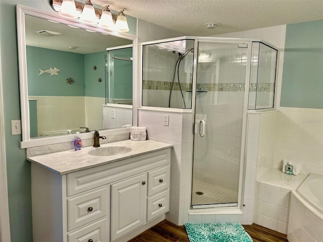 bathroom featuring tile walls, a textured ceiling, independent shower and bath, vanity, and wood-type flooring