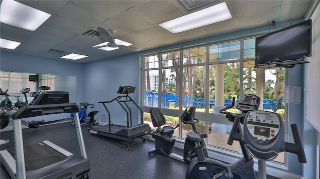 exercise room featuring a wealth of natural light, ceiling fan, and a drop ceiling