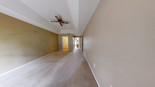 unfurnished room with ceiling fan, a raised ceiling, and a textured ceiling