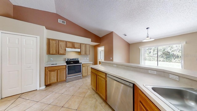 kitchen featuring lofted ceiling, sink, decorative light fixtures, light tile patterned floors, and stainless steel appliances