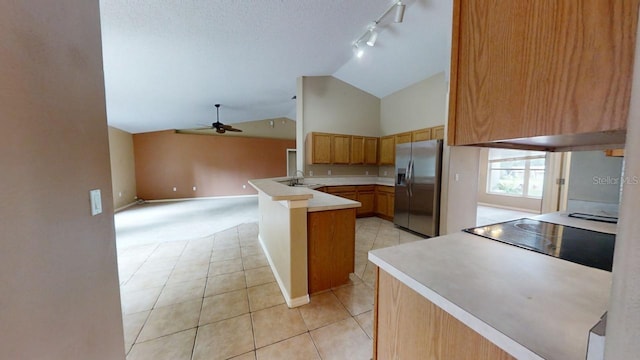 kitchen featuring lofted ceiling, light tile patterned floors, ceiling fan, stainless steel refrigerator with ice dispenser, and kitchen peninsula