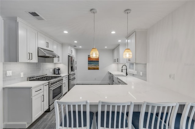 kitchen with pendant lighting, white cabinets, appliances with stainless steel finishes, sink, and kitchen peninsula