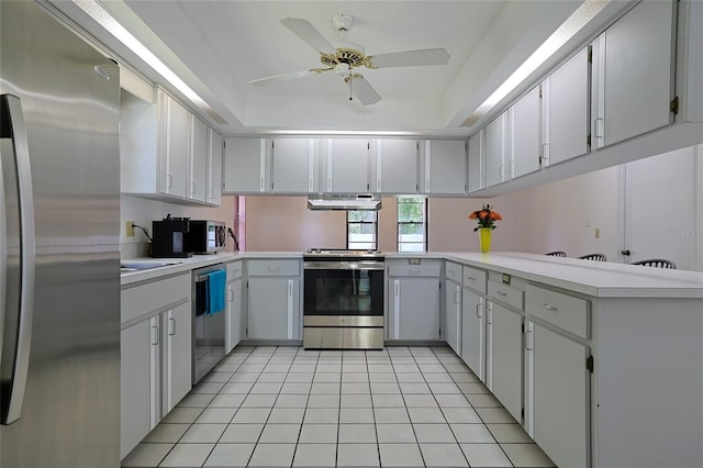 kitchen featuring a raised ceiling, white cabinetry, light tile patterned floors, kitchen peninsula, and stainless steel appliances